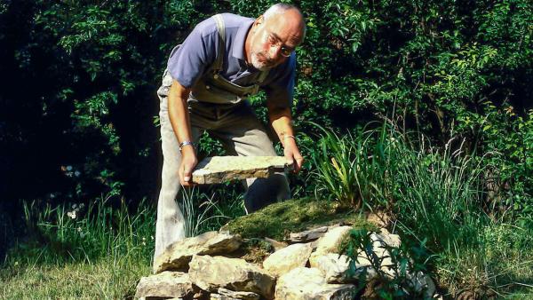 Bild 1 von 1: Peter (Peter Lustig) baut einen Eidechsenhügel in seinem Garten. Er ist gespannt, wann die ersten Drachenbabys bei ihm einziehen.