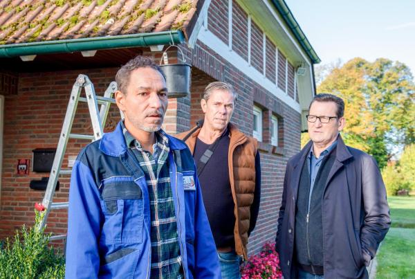 Bild 1 von 3: Im Bild: Khalid Hadam (Raschid Daniel Sidgi, l.) erfährt durch Finn (Sven Martinek, M.) und Lars (Ingo Naujoks, r.) vom Tod seiner Frau. Er ist sichtlich mitgenommen.