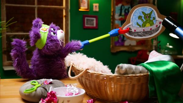 Bild 1 von 4: MiWau hält eine selbstgemalte Zeichnung von einer Katze in einem Ufo vor das Teleskop.© rbb/Anderthalb - Honorarfreie Verwendung gemäß AGB im redaktionellen Zusammenhang mit genannter Sendung bei Nennung \