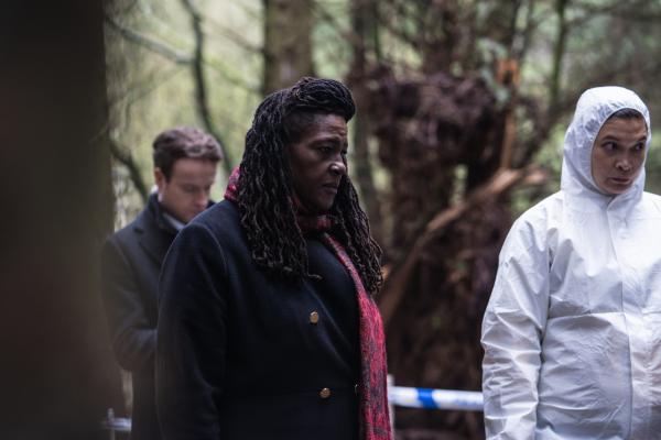 Bild 1 von 9: Harper (Andrew Gower, l.) und Ellis (Sharon D Clarke, M.) stehen mit der Gerichtsmedizinerin CSI Christine Bennett (Kirsten Foster, r.) am Leichenfundort, einem Waldstück.
