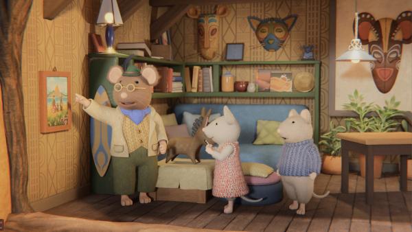 Bild 1 von 3: Herr Grummel (l.) zeigt Julia (M.) und Sam (r.) in seiner Wohnung ein Bild, das ihn als Kind mit seinen Eltern zeigt. Dabei erzählt er, dass auch er von Julias Heimatinsel stammt, aber schon länger im Mäusehaus wohnt.