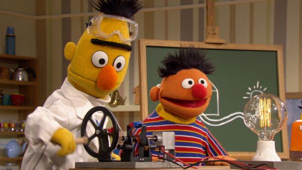 Bild 1 von 2: Bert (l.) möchte Ernie (r.) zeigen, wie ein Stromkreis funktioniert.