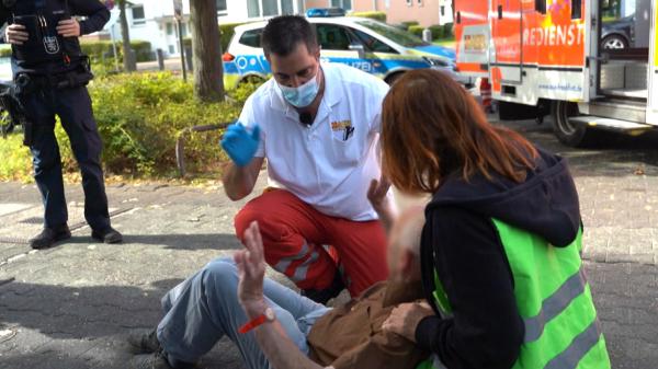 Bild 1 von 2: Notfallsanitäter Chris Grüne kümmert sich um einen älteren Herrn, der gestürzt ist