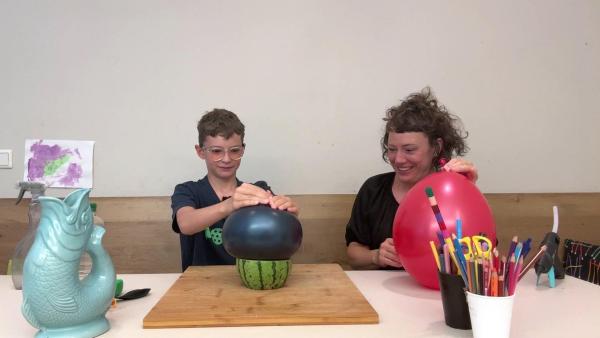 Bild 1 von 1: Im Bild: Esther testet, ob man eine Wassermelone mit Hilfe eines Luftballons abdecken kann.