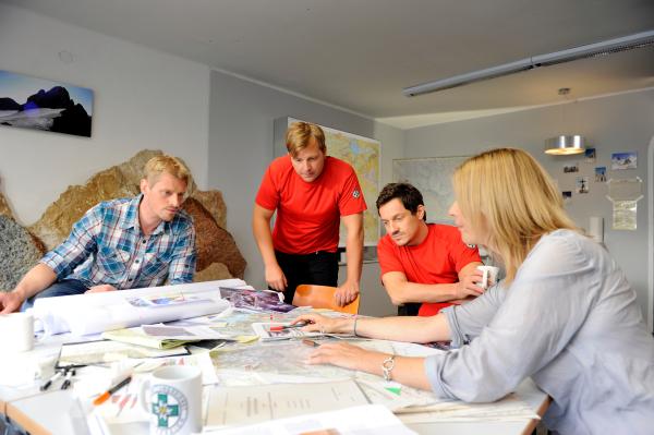 Bild 1 von 2: Die Bergretter besprechen den bevorstehenden Einsatz. Andreas Marthaler (Martin Gruber, l.), Toni Stössl (Martin Klempnow, 2.v.l.), Tobias Herbrechter (Markus Brandl, 2.v.r.) und Bea Kleinert (Paula Paul, r.).